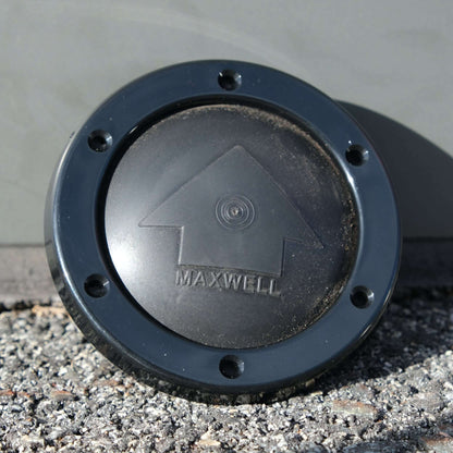 Maxwell FootSwitch Bezel Black resting on gravel surface with logo viewable.