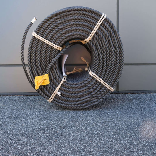 ROPE PE 12MM X 220M BLACK wrapped neatly, showcasing its durability and sleek design on a gray background.