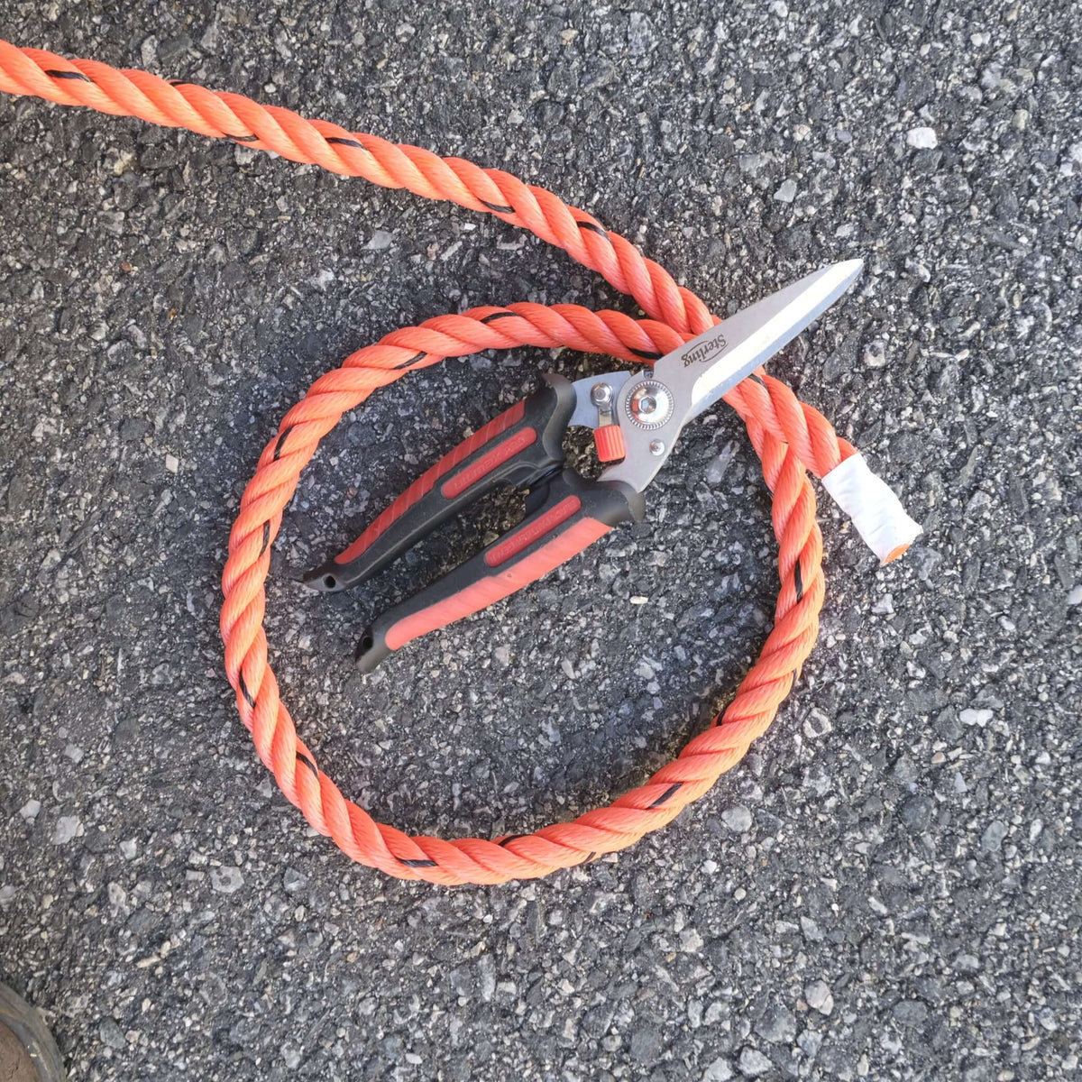 ROPE PE 14MM X M with scissors on asphalt surface, showcasing durability and versatility for demanding tasks.