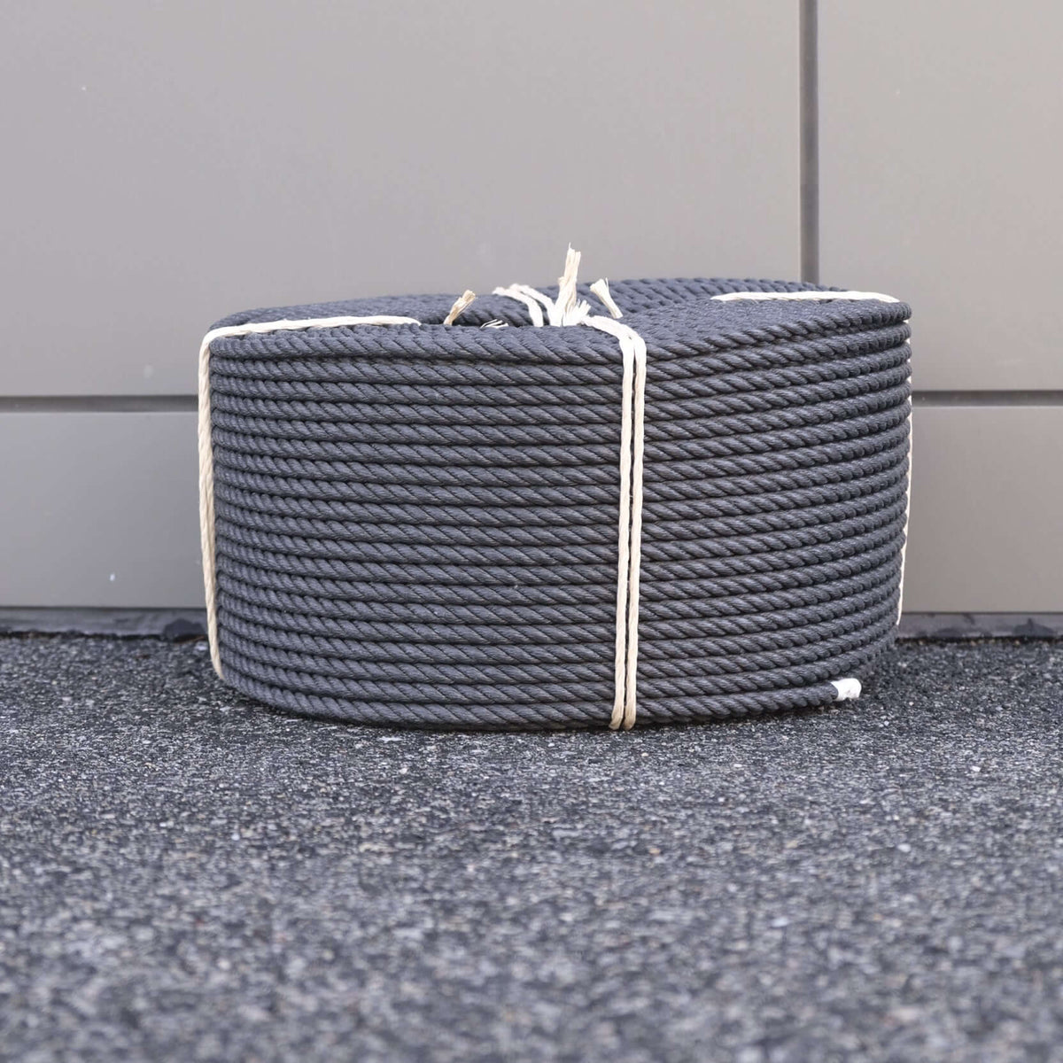 ROPE PP 12MM X 220M BLACK rolled and bundled on a surface, showcasing its high tensile strength and durability.