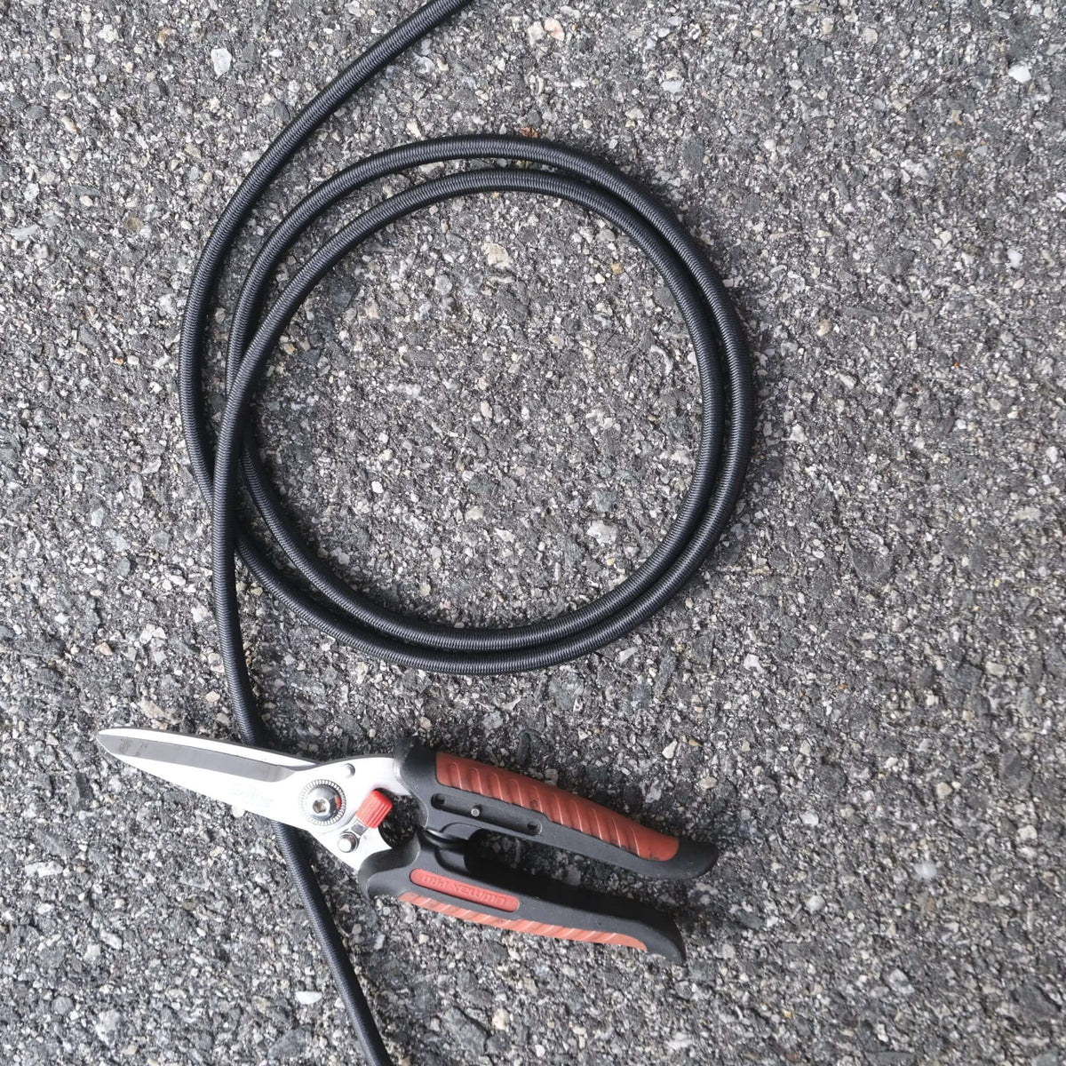 7mm Black Shock Cord x m with scissors on asphalt surface for professional crayfishing and secure fastening solutions.