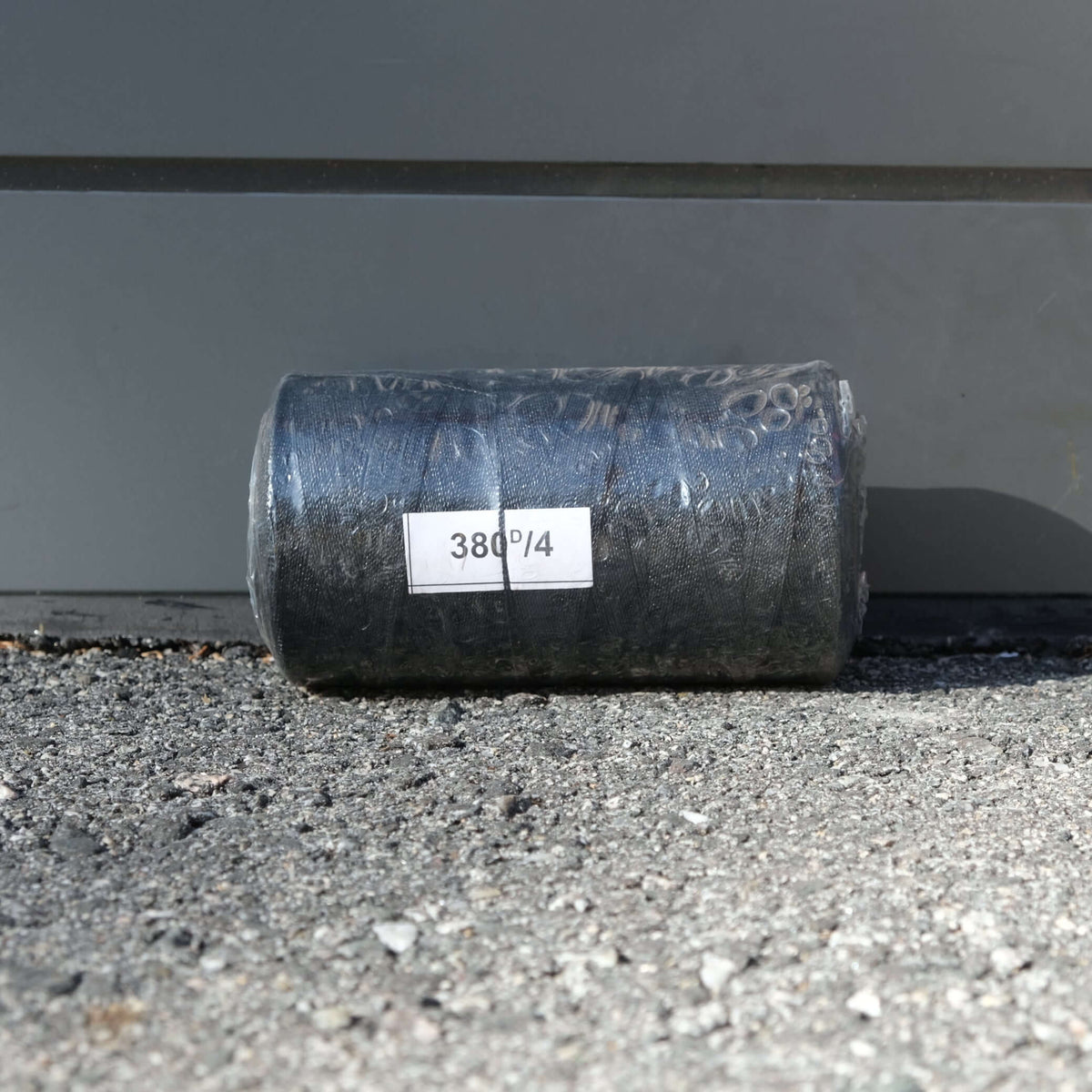 TWINE PE 4PLY X 500G BLACK roll on gravel surface, suitable for outdoor repairs and hanging nets.