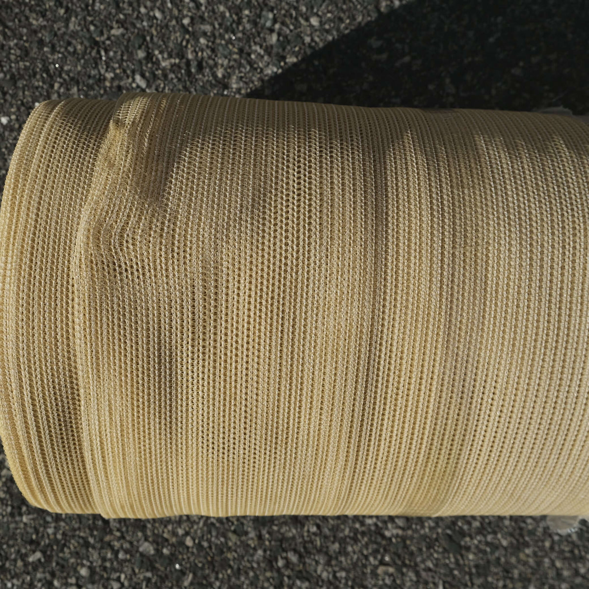 Close-up of SHADECLOTH 35% 3.66M X 50M BEI roll, showing beige mesh texture for UV protection and plant growth.
